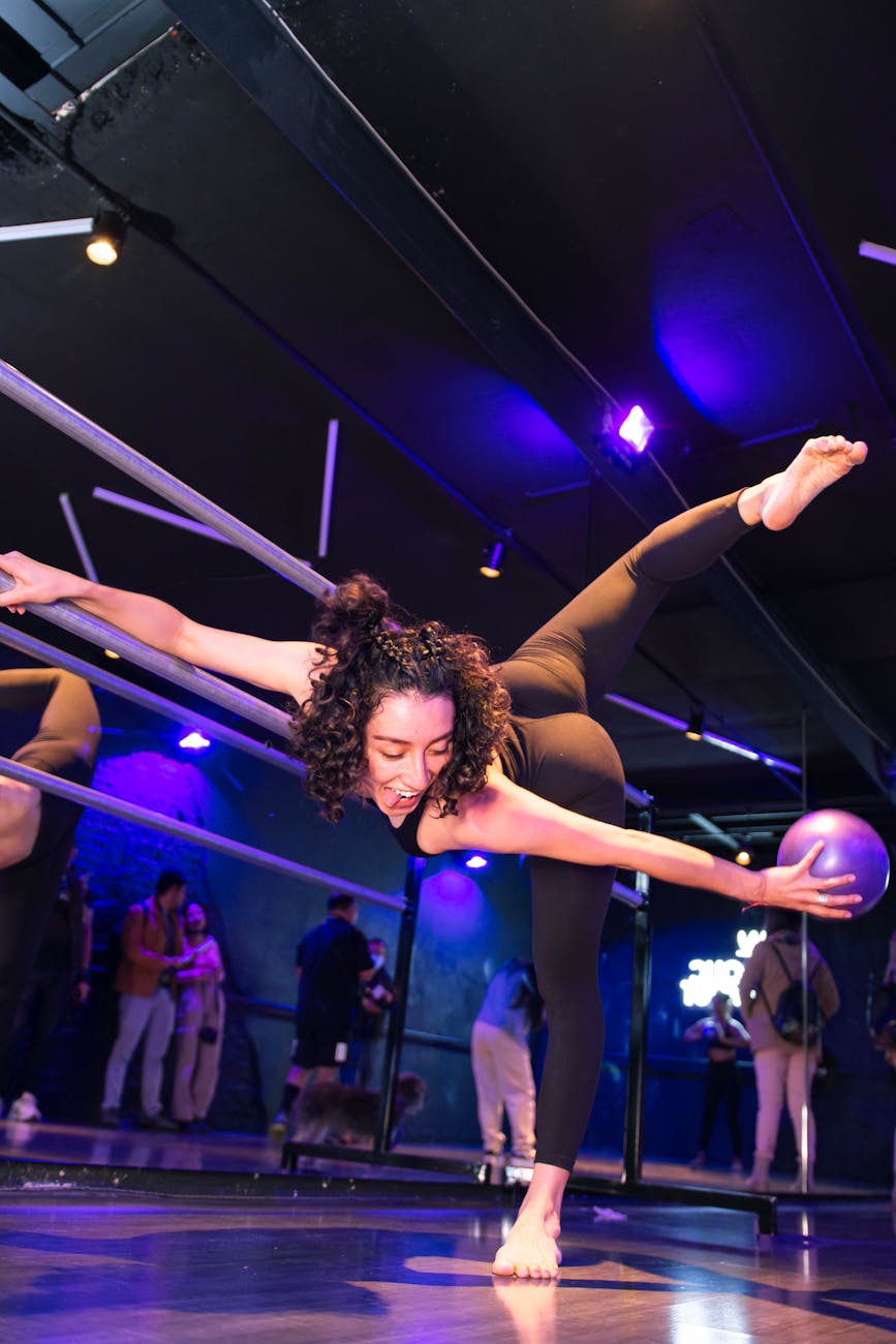 Woman performing a challenging yoga balance pose in a stylish, dark studio.